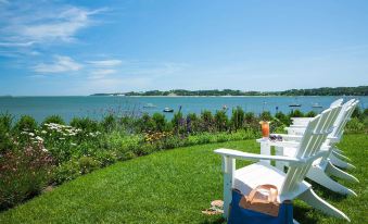 a serene view of a lake with boats , flowers , and grassy area in the foreground at Wequassett Resort and Golf Club