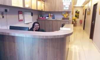 a woman sitting behind a wooden reception desk in a hotel lobby , smiling at the camera at Muar Golden Horse Hotel
