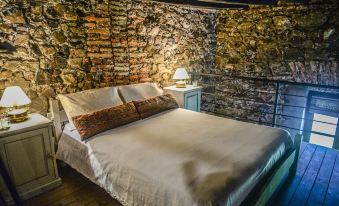 a cozy bedroom with a large bed and a stone wall , creating a warm and inviting atmosphere at Santa Virginia