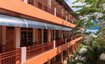 an orange building with a blue awning on the side , surrounded by trees and other buildings at Hotel Elvin