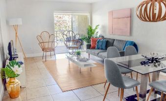 a modern living room with a gray couch , blue chairs , and a dining table , all situated near a window at Coral Reef at Key Biscayne