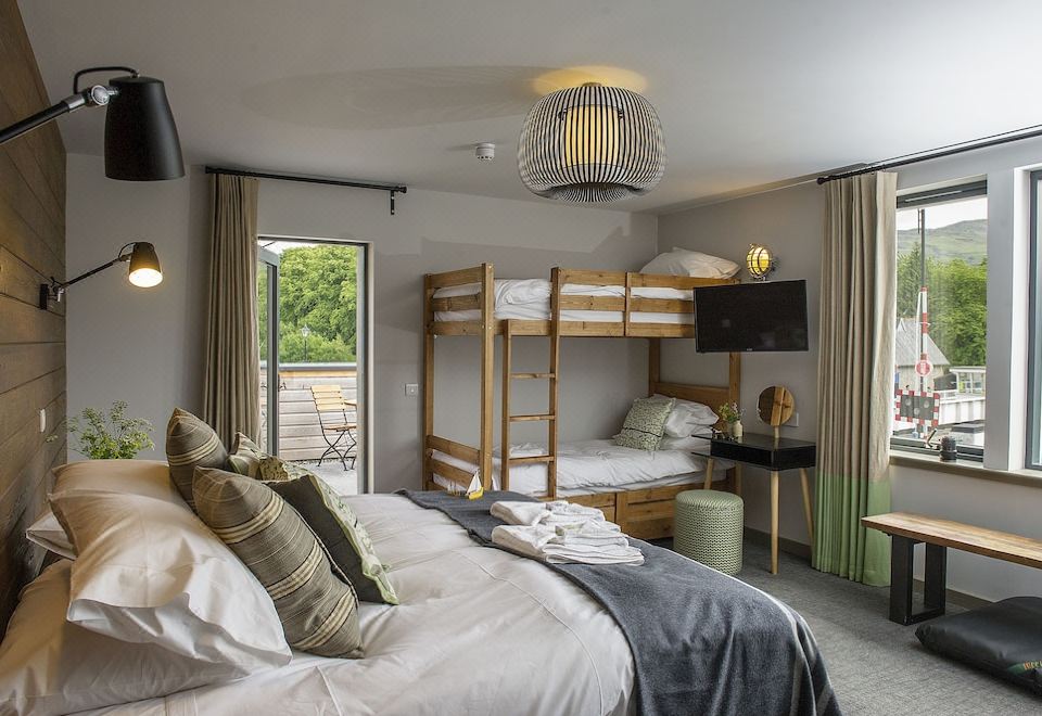 a cozy bedroom with a bunk bed , a tv , and a desk , all set against a backdrop of trees at Lock Chambers, Caledonian Canal Centre