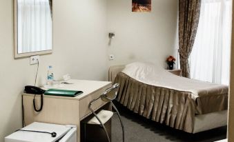 a small hotel room with a single bed , a desk , a chair , and a television at Yugorsky