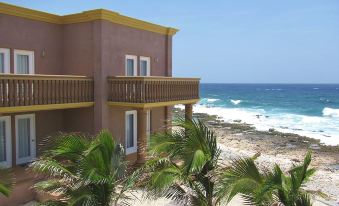 a beach house with a balcony overlooking the ocean , surrounded by palm trees and white sand at Kings Point