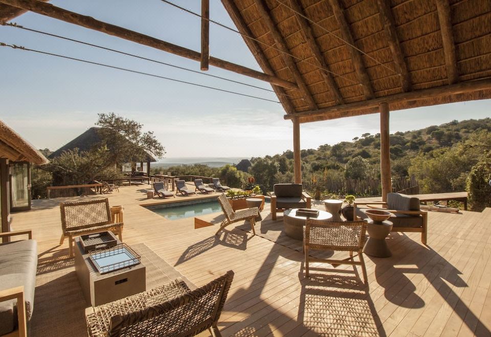 a large outdoor patio with a pool and dining area overlooking a beautiful view of the outdoors at Bukela Game Lodge - Amakhala Game Reserve