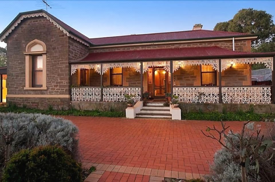 a large brick house with a red roof , surrounded by potted plants and a red brick walkway at Copper House