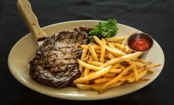 a white plate with a steak and fries , accompanied by a fork and a knife at GreenLinks Golf Villas at Lely Resort