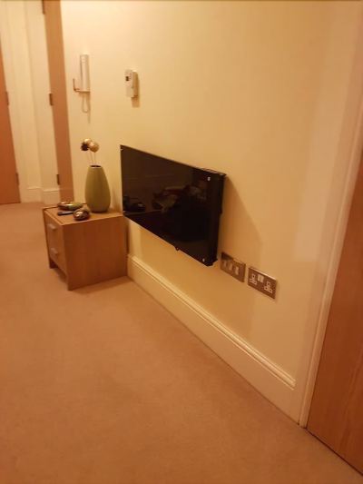 a living room with a flat screen tv mounted on the wall , next to a small wooden table at Knights