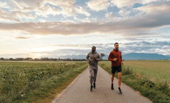 two men are running on a dirt road with a field in the background , enjoying their time outdoors at Everness Hotel & Resort