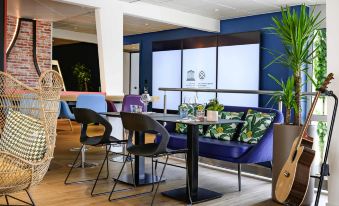 a modern office space with blue walls , wooden floors , and various seating options such as couches and chairs at Novotel Dijon Sud