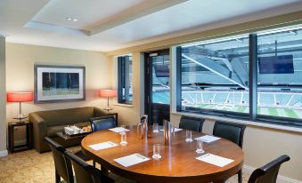 a conference room with a wooden table , chairs , and papers set up for a meeting at London Twickenham Stadium Hotel, a Member of Radisson Individuals