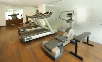 a well - equipped gym with various exercise equipment , including treadmills and stationary bikes , arranged in a spacious room at Four Points by Sheraton Ahmedabad