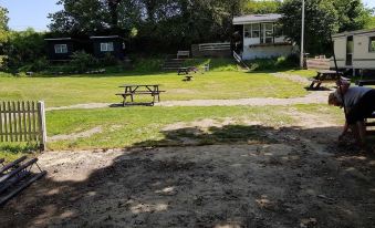 a picnic area with benches and a barbecue grill in the grassy area near a fence at Paradiset