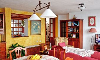 a cozy living room with yellow walls , a dining table , chairs , and a bookshelf filled with books at Titi