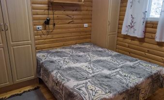 a bed with a gray and white patterned blanket is in a room with wooden walls at Kuikka