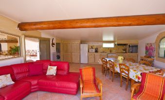 a living room with a red couch , wooden dining table and chairs , and an open kitchen at Cucuron