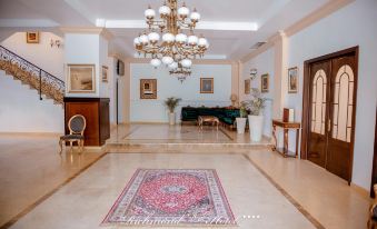 a large , well - lit room with a wooden floor and ornate chandelier features a pink rug on the floor at Richmond Hotel