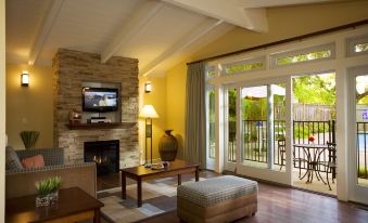 a cozy living room with a brick fireplace , a television , and a door leading to a patio at The Cottages Hotel