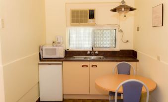a small kitchen with a dining table and chairs , a microwave , sink , and a refrigerator at Motel Lodge