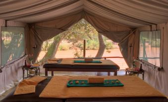 a wooden table with green tablecloth in front of a tent , surrounded by tables and chairs at Sarova Shaba Game Lodge