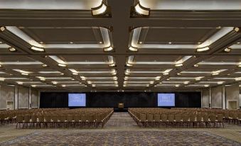 an empty conference room with rows of chairs and two large screens on the wall at Hyatt Regency Sacramento