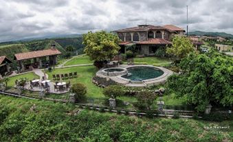 a large , two - story house with a swimming pool in the backyard , surrounded by lush greenery and trees at Hacienda Los Molinos Boutique Hotel & Villas