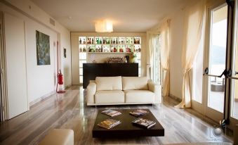 a spacious living room with white couches , a dining table , and a bar area with various bottles at La Castellana