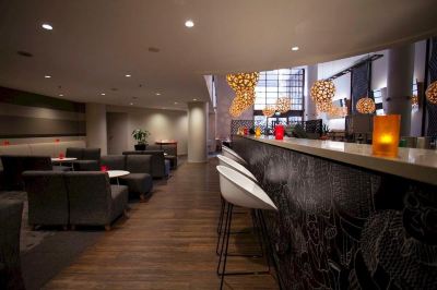 a modern bar area with a black and white marble counter , multiple chairs , and several potted plants at Ibis Melbourne Hotel and Apartments