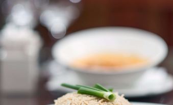 a white plate with a small amount of rice , accompanied by a bowl of soup at Raphael's Hotel