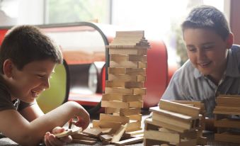 A young boy and girl are playing with blocks on a table, while another child is sitting at the same table at Remis Hotel