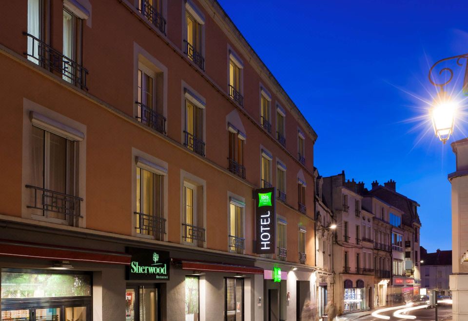 a hotel building with multiple floors , located on a city street at night , illuminated by lights at Ibis Styles Chaumont Centre Gare