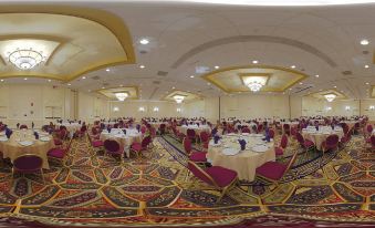 a large , well - decorated banquet hall with multiple dining tables set for a formal event , including round tables and chairs at Winston-Salem Marriott