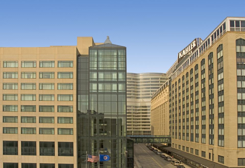 "a large building with a glass facade is shown from an elevated perspective , with the words "" elite "" and "" amex "" visible" at Kahler Grand Hotel