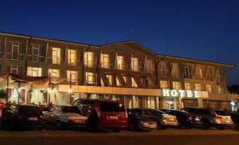 a large hotel building with a parking lot in front of it at night , illuminated by lights at Hotel Perla