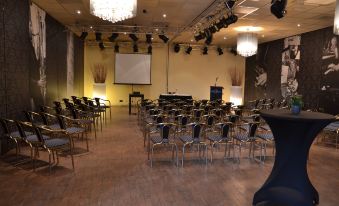a large conference room with rows of chairs arranged in a semicircle , ready for a meeting or event at Fletcher Hotel - Restaurant Heiloo