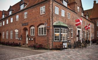 a brick building with a red roof and a danish flag hanging from the eaves at Hotel Dagmar
