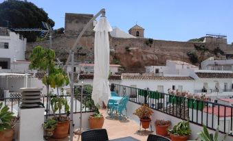 a balcony with white umbrellas and chairs , surrounded by potted plants , overlooking a cityscape at Casa del Sol