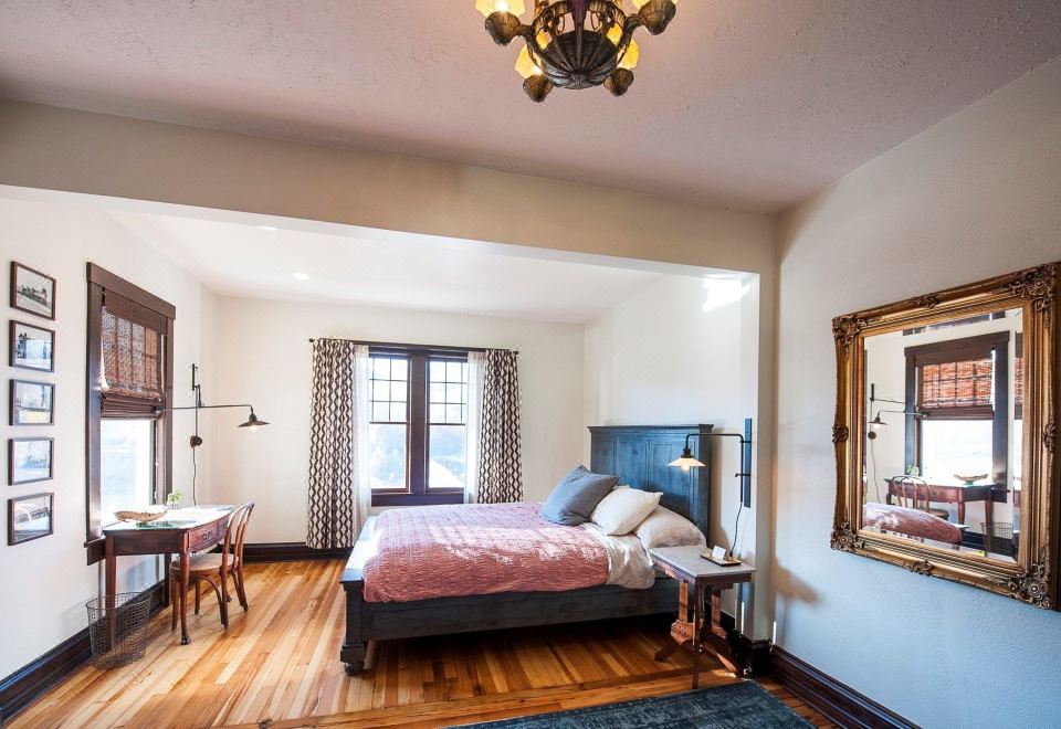 a spacious bedroom with hardwood floors , a large bed , and a mirror on the wall at Marshall House Inn