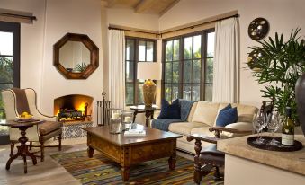 a cozy living room with a large window , a fireplace , and a fireplace in the corner at Rancho Valencia Resort and Spa