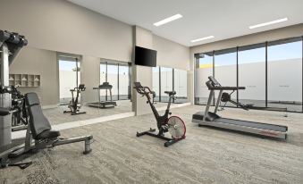 a modern gym with various exercise equipment , including treadmills and stationary bikes , positioned near large windows that offer views of the outdoors at Quest Innaloo
