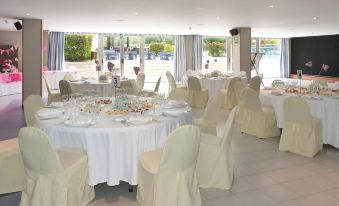 a large dining room with round tables covered in white tablecloths and chairs arranged around them at Sol Costa Daurada