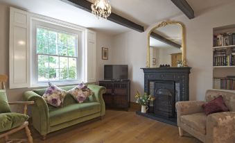 a cozy living room with a green couch , a fireplace , and a tv mounted on the wall at Marsh House Farm