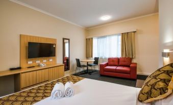 a modern hotel room with a red couch , white bed , and a flat - screen tv on the wall at Best Western Mahoneys Motor Inn