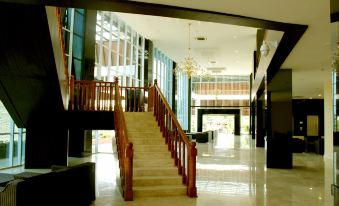 a modern building with an open atrium , featuring a staircase and large windows , as well as a chandelier hanging from the ceiling at Merapi Merbabu Hotels Bekasi