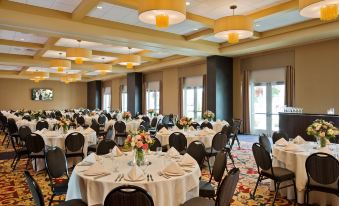 a large , well - lit dining room filled with round tables and chairs , ready for a formal event at Saratoga Casino Hotel