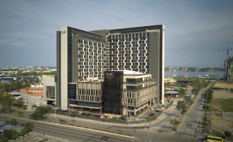 a large , modern hotel building with multiple floors and balconies , situated on a busy street near a body of water at bai Hotel Cebu