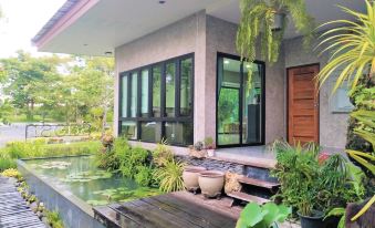 a modern house with a wooden deck and potted plants , situated near a tranquil pond at Baiboon Resort