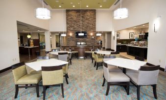 a large dining area with several tables and chairs , a television mounted on the wall , and pendant lights at Homewood Suites by Hilton Houma