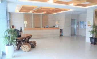 a modern office reception area with a wooden table , chairs , and a white floor , surrounded by white walls and wooden ceiling at Ocean Hotel