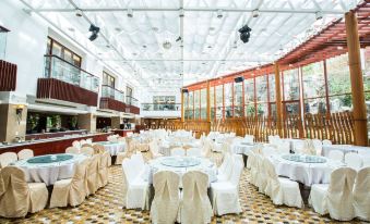 a large banquet hall filled with round tables and chairs , ready for a formal event at Alishan House